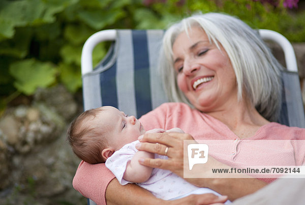 Woman with grandchild sitting in lawn chair  smiling