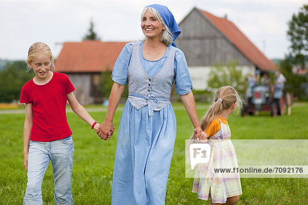 Germany  Bavaria  Grandmother with children walking in front of farmhouse