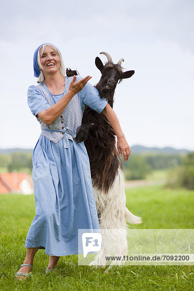 Mature woman playing with goat on farm
