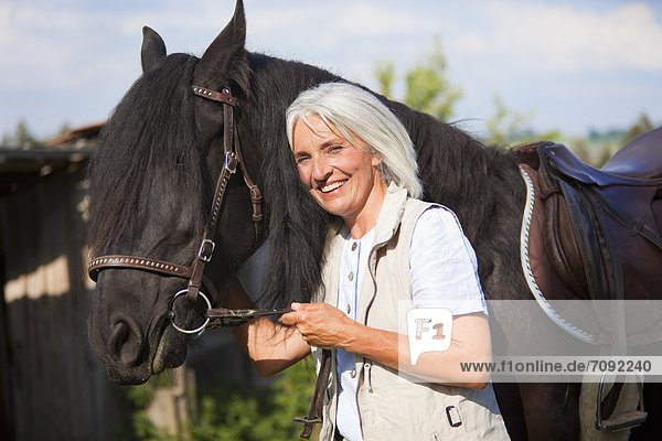 Mature woman hugging horse
