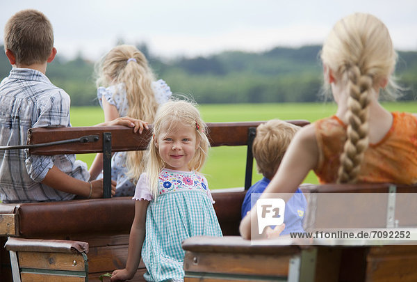 Deutschland  Bayern  Kindergruppe auf Wagen sitzend