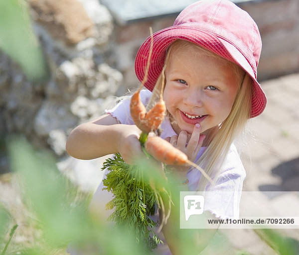 Girl picking carrots in garden