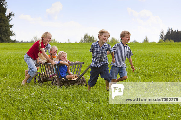 Germany  Bavaria  Group of children playing with hand cart