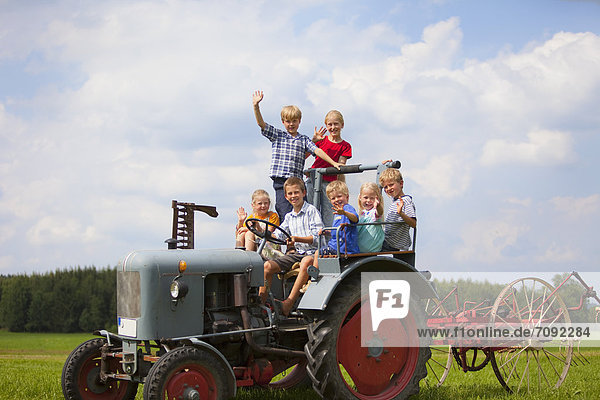 Germany  Bavaria  Group of children sitting in old tractor