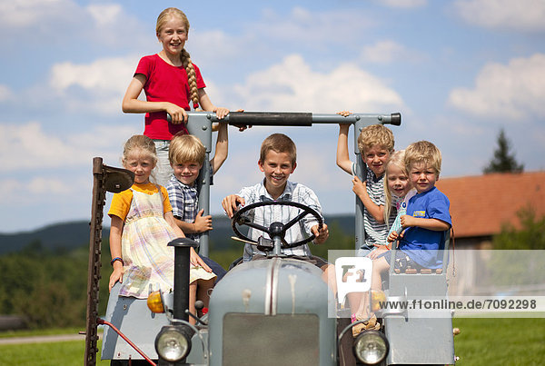 Germany  Bavaria  Group of children sitting in old tractor