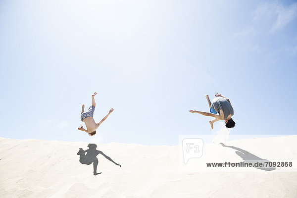 France  Two Boys jumping on sand dune
