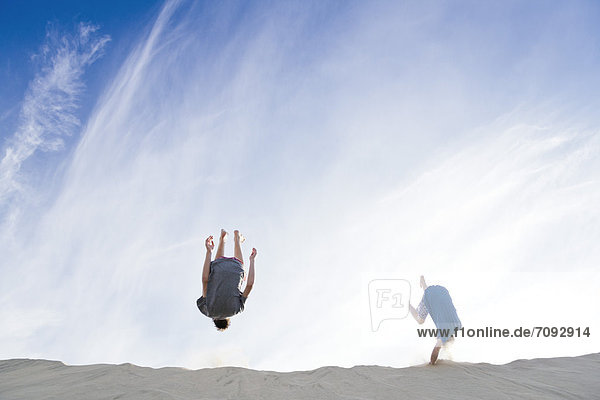 Frankreich  Zwei Jungen springen auf Sanddüne