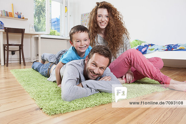 Germany Berlin Family lying on floor smiling portrait