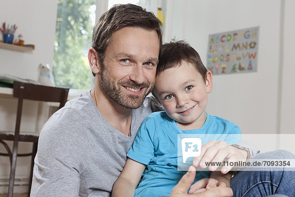 Germany  Berlin  Father and son at home  smiling  portrait
