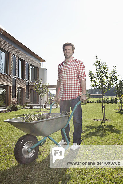 Mature man with wheelbarrow in garden