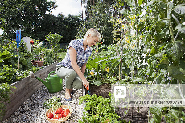 Mature woman with vegetables in garden