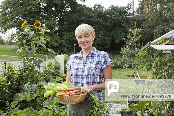 Mature woman with vegetables in garden