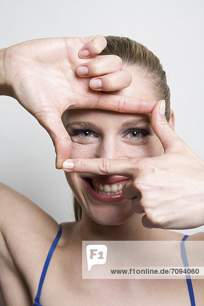 Young woman looking through finger frame  close up