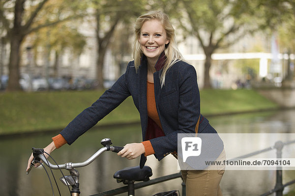 Europe  Germany  North Rhine Westphalia  Duesseldorf  Young woman with bicycle  smiling  portrait