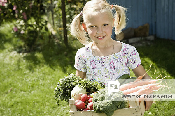 Girl holding vegetables in crate  smiling  portrait
