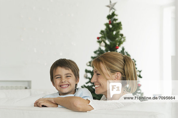 Mutter und Sohn sitzen auf der Couch vor dem Weihnachtsbaum
