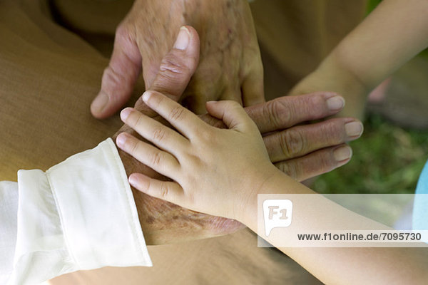 Child's hand holding elderly person's hand