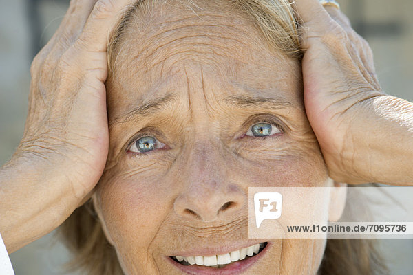 Senior woman holding head  distressed expression on face