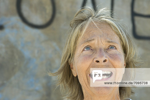 Senior woman looking up with fearful expression on face