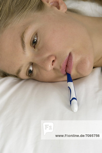 Young woman with thermometer in mouth  cropped