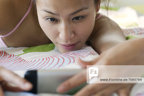 Young woman lying down  looking at cell phone