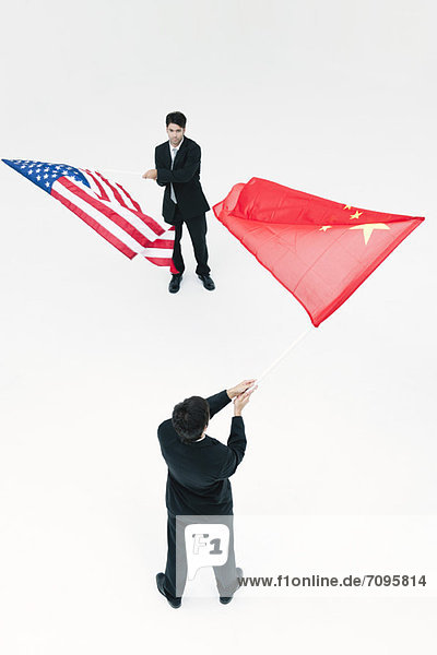 Männer  die von Angesicht zu Angesicht stehen und chinesische und amerikanische Flaggen schwenken.