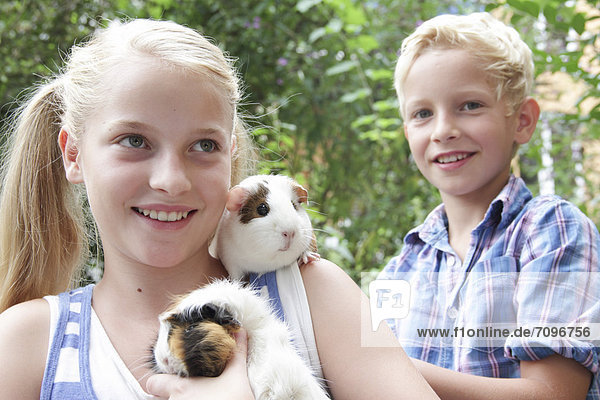 Girl and boy holding guinea pigs