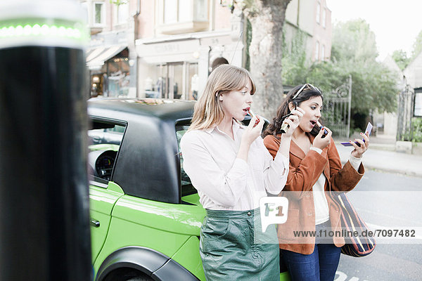 Frauen beim Auftragen von Lippenstift auf der Stadtstraße