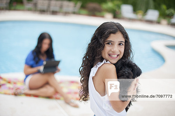 Lächelndes Mädchen mit Welpe am Pool