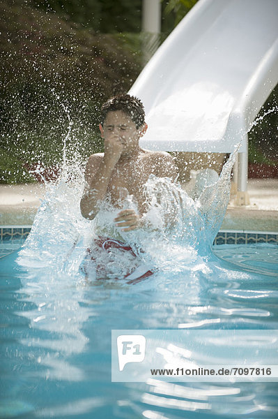 Junge auf Wasserrutsche spritzt in den Pool