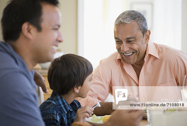 Hispanic grandfather,  father and son eating dinner