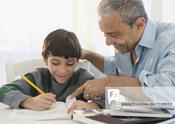 Hispanic grandfather helping grandson with homework