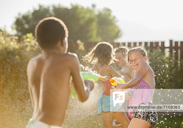 Children squirting each other with water guns