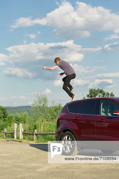 Young man jumping off car