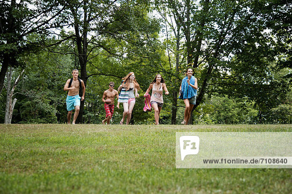 Five friends running on grass  front view