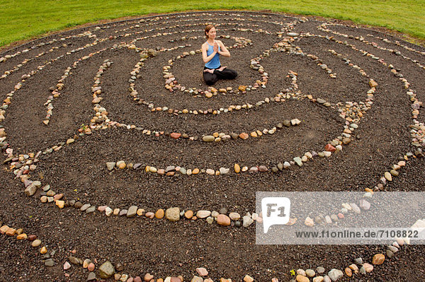 Frau meditiert im Steinlabyrinth