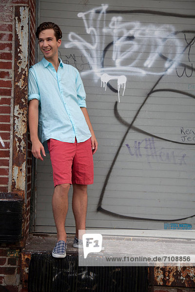 Young man standing in front of graffiti  portrait