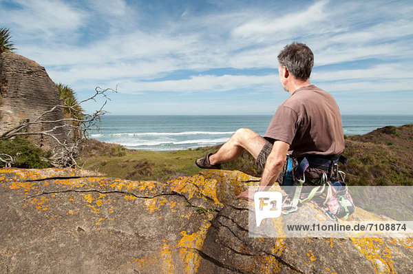 Rock climber at top of rock taking in scenery  Ruapuke  Raglan  New Zealand