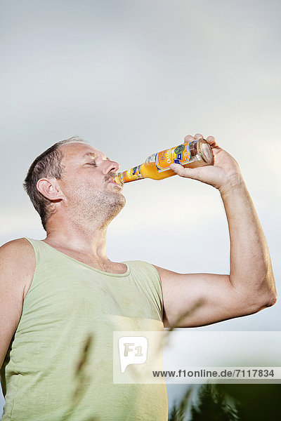 Mann trinkt Erfrischungsgetränk aus der Flasche