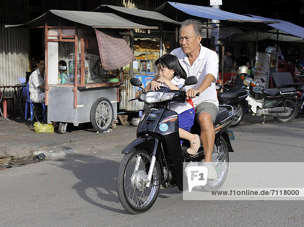 Man with a child on a motor scooter  Phnom Penh  Cambodia  Southeast Asia  Asia
