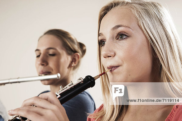 Two teenage girls playing oboe and transverse flute