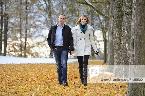 Glückliches Paar geht in herbstlicher Umgebung spazieren