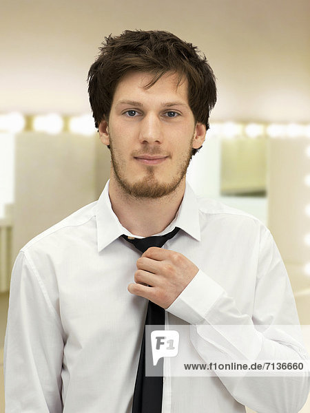 Portrait of a young man with a beard straightening his tie  friendly  relaxed