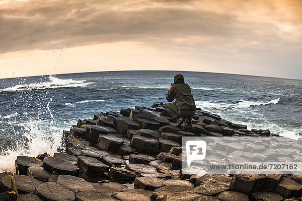 Man taking photo with a smartphone  Giant's Causeway  basalt columns  Causeway Coast  County Antrim  Northern Ireland  United Kingdom  Europe
