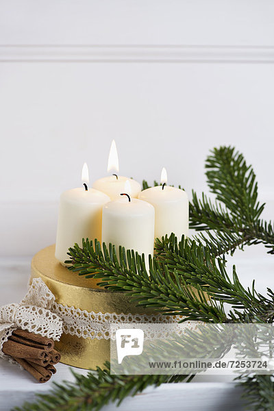 Adventskranz mit weißen Kerzen und Zimtstangen