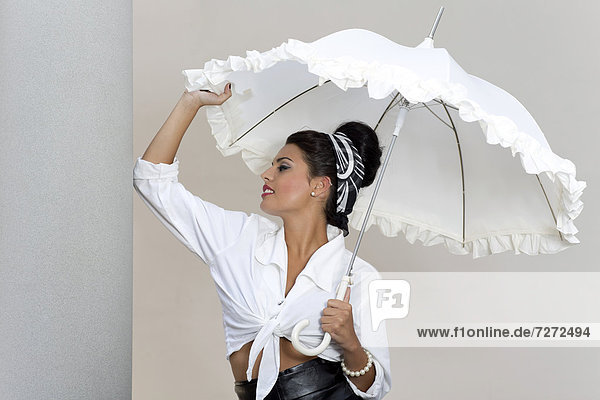 Junge Frau mit Hochsteckfrisur  weißem Hemd und weißem Schirm