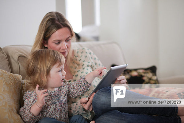 Mutter mit Tochter auf digitales Tablett zeigend
