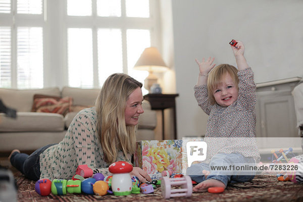 Mutter und Tochter spielen mit Spielzeug auf dem Wohnzimmerboden