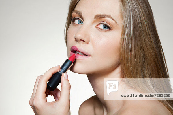 Frau beim Auftragen von Lippenstift