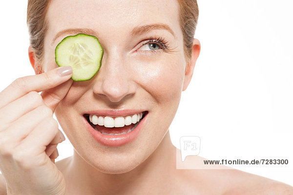 Woman holding a cucumber slice to her eye